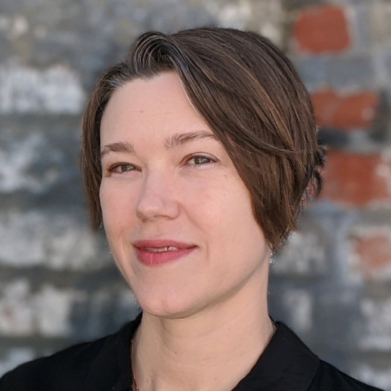 Portrait of Erin Daily in front of an aged brick wall